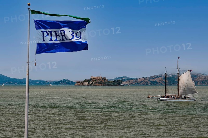 Flag of Pier 39 and historic sailboat in San Francisco Bay