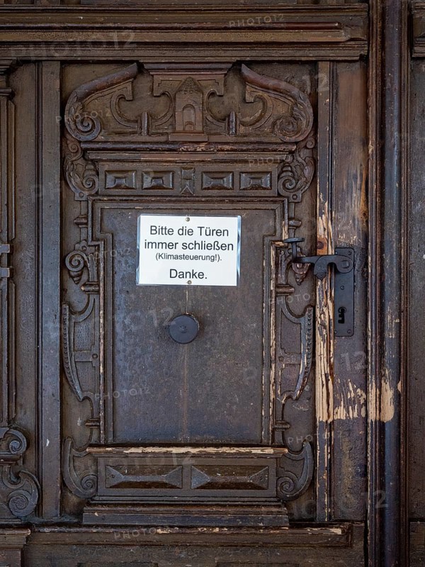 Portal of the Catholic parish church of St. George with sign 'Please always close the bags
