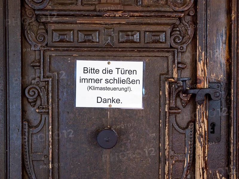 Portal of the Catholic parish church of St. George with sign 'Please always close the bags