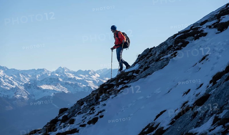 Mountaineers on the rocky summit ridge with the first snow in autumn