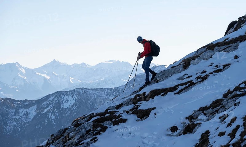 Mountaineers on the rocky summit ridge with the first snow in autumn