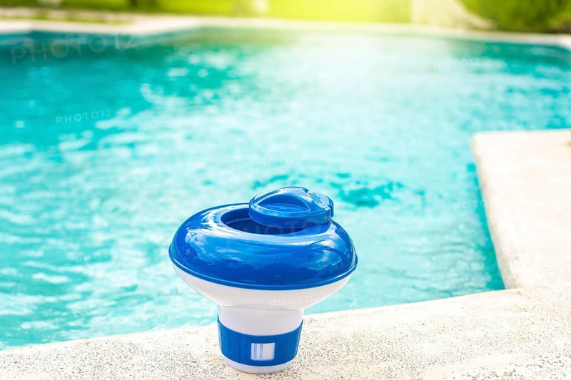 A chlorine dispenser for swimming pools with blue water in the background. Dosing float for swimming pool chlorination