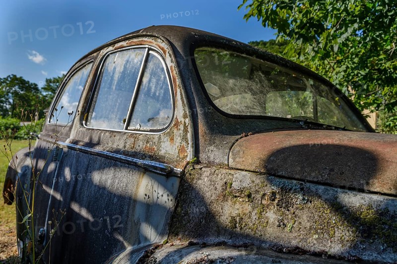 Old car rolled for scrapping in a meadow. Alsace