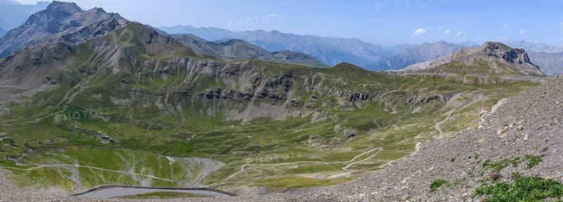 View from Cime de la Bonette on high alpine mountain landscape with road to Col de la Bonette in the background on the right
