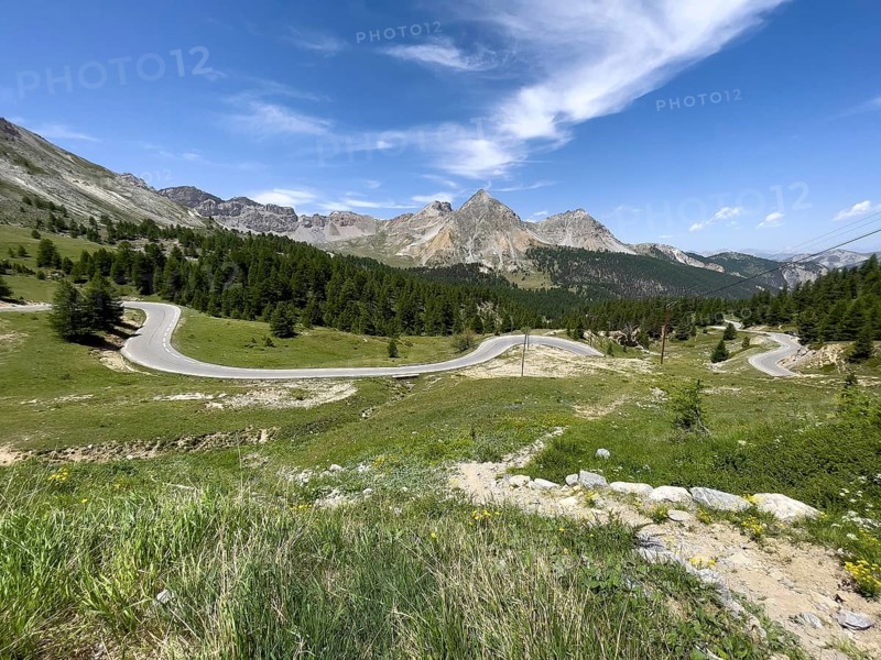 View over wild alpine meadow on winding alpine road Mountain road in front of Col de l Izoard