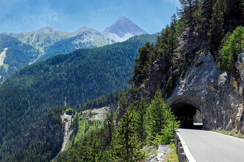 Mountain road with tunnel on steep rock face with tree cover