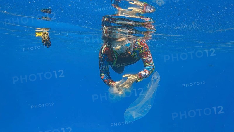 Woman collects plastic garbage underwater clean up of a dirty discarded plastic bags