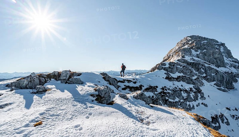 Climbers on the rocky summit ridge with first snow in autumn