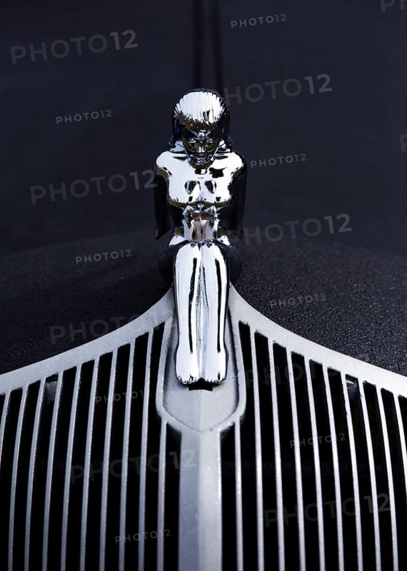 A naked woman as a radiator mascot on a vintage car