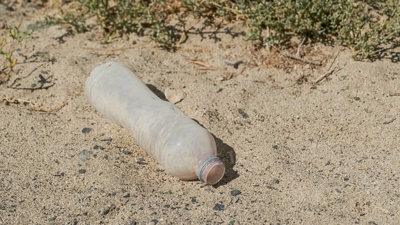 Close-up of plastic bottle in the desert. Plastic pollution in sandy desert. Egypt