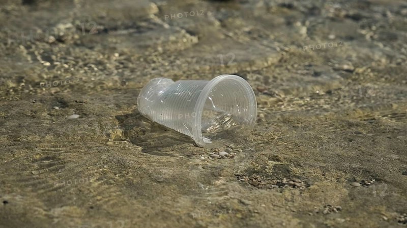 Transparent plastic cup is carried away by the wind to the sea in the coastal zone. Plastic pollution of the surf zone. Red sea