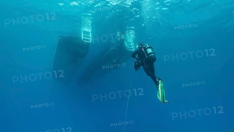 Scuba diver swim towards diving boat in blue water. Mediterranean Sea