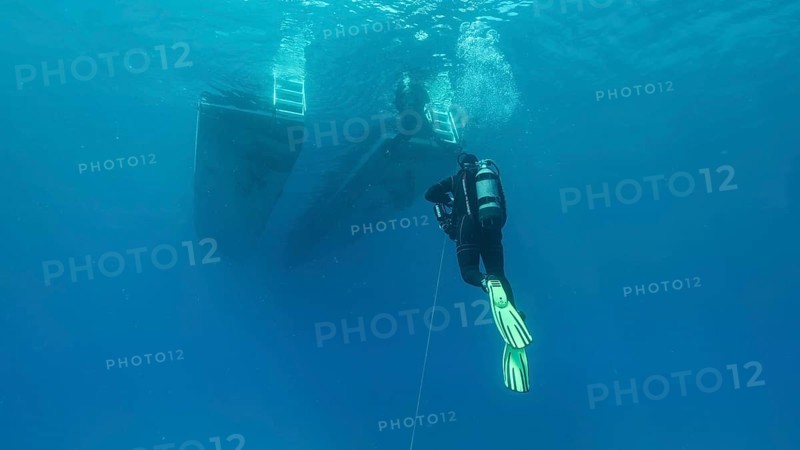 Scuba diver swim towards diving boat in blue water. Mediterranean Sea