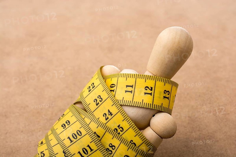Yellow color measuring tape wrapped on wooden man