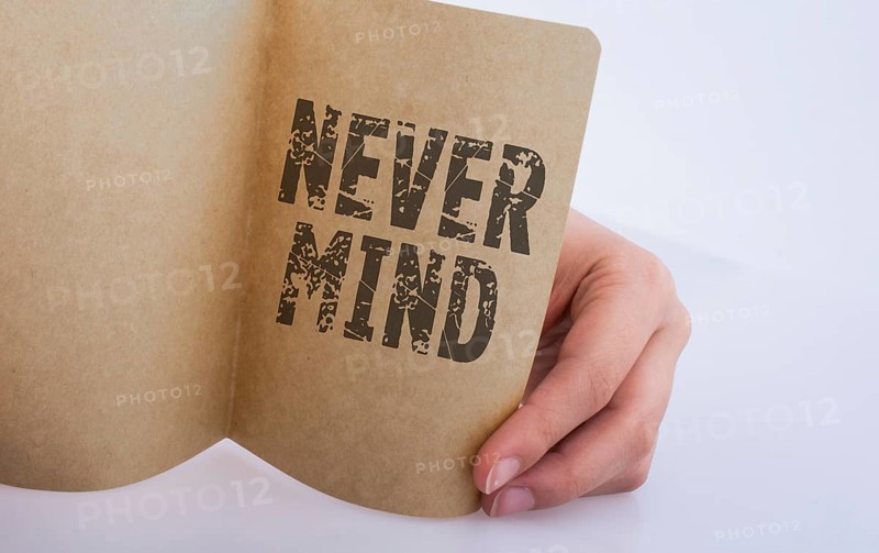 Hand holding a sheet of paper NEVER MIND on a white background