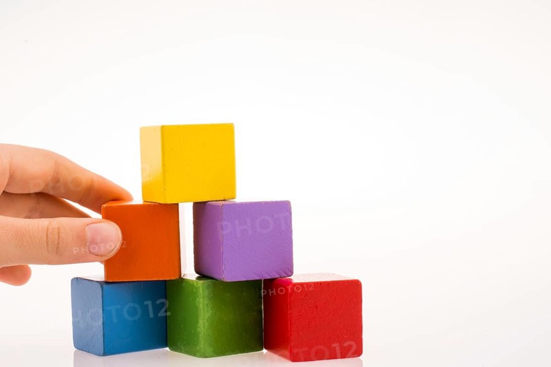 Hand playing with colorful cubes on a white background