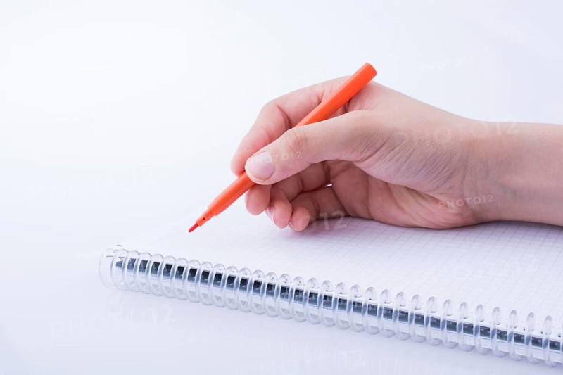 Hand writing on a Notebook with a pen on a white background