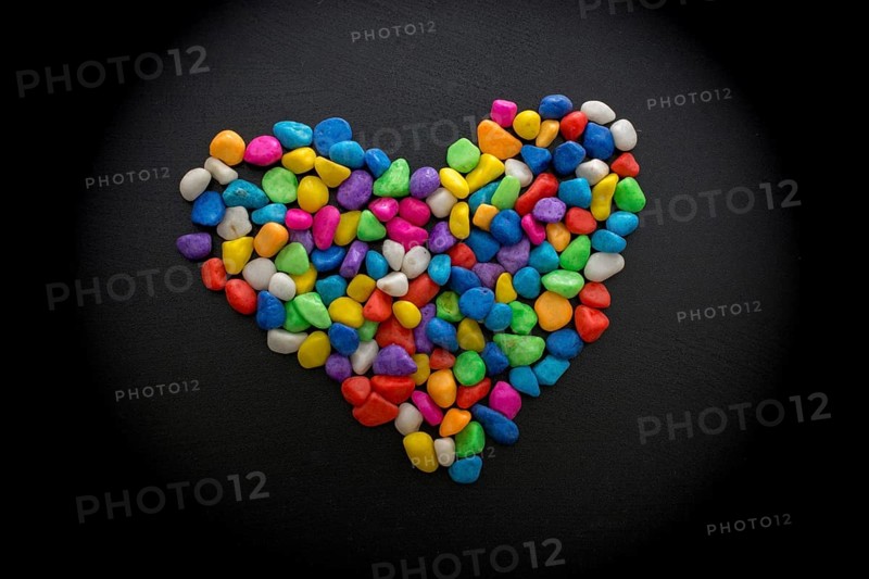 Colorful little pebbles form heart shape on black