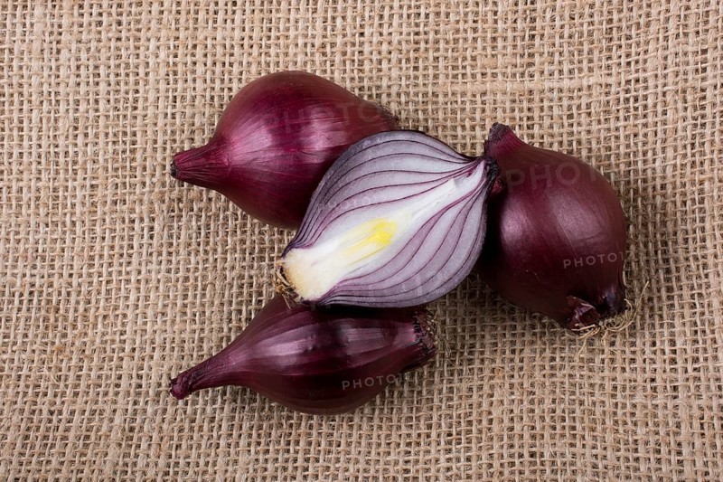 Red onion bulb cut in half on a certain background