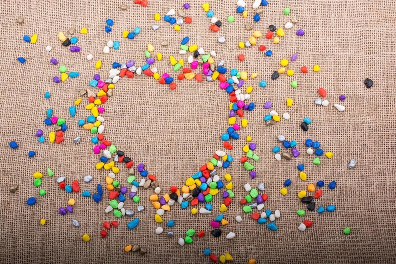 Colorful little pebbles form a heart shape on canvas ground
