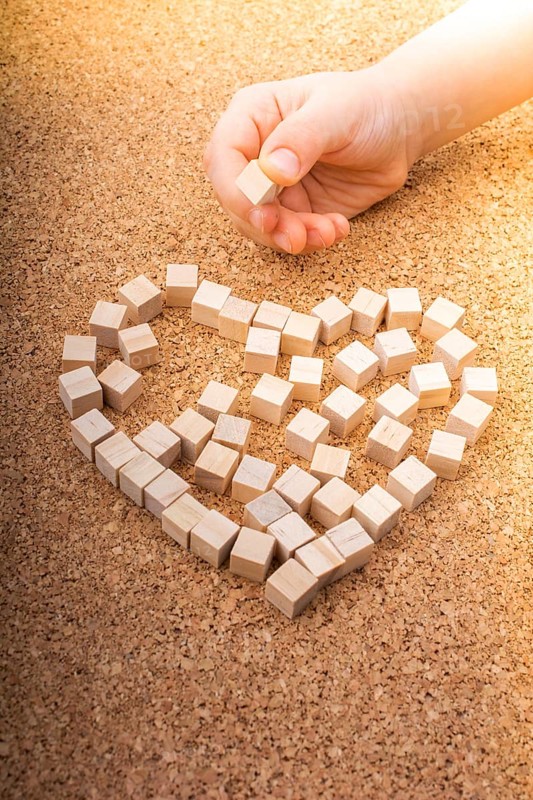 Little wooden cubes form heart shape or valentines day symbol and hand