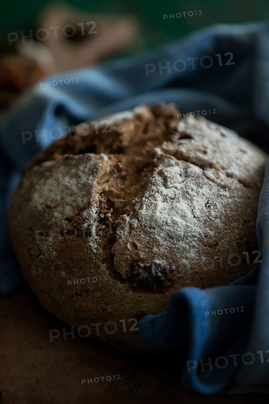 Freshly baked bread with walnuts and pickled tomatoes on a wooden board