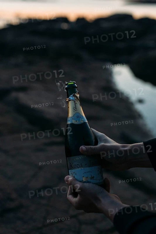 Opening a bottle of champagne on the beach
