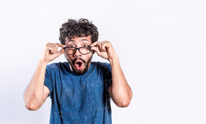Surprised handsome man taking off his glasses, Person taking off his glasses surprised by a promotion