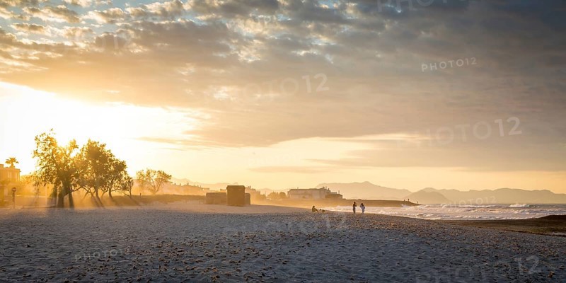 Evening atmosphere at the sandy beach playa in Son Serra de Marina, Tramuntana Mountains in the back