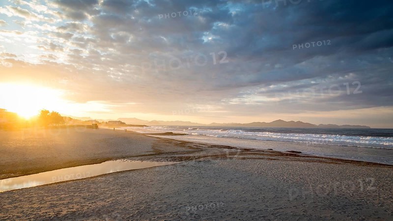 Sunset at the sandy beach playa in Son Serra de Marina, Tramuntana Mountains in the back