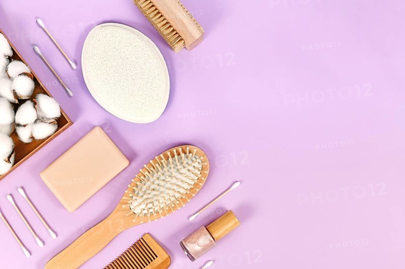 Eco friendly wooden beauty and hygiene products like comb and soap arranged on violet background,