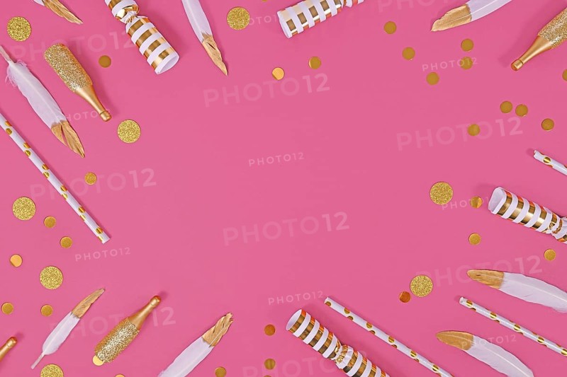 Party flat lay with golden and white decoration like confetti and feathers forming border around pink background,