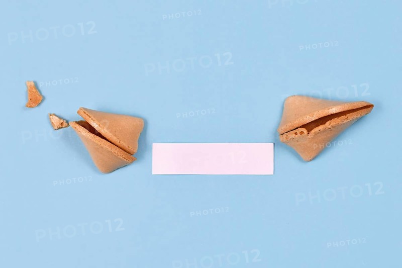 Open fortune cookie with note without text on blue background,