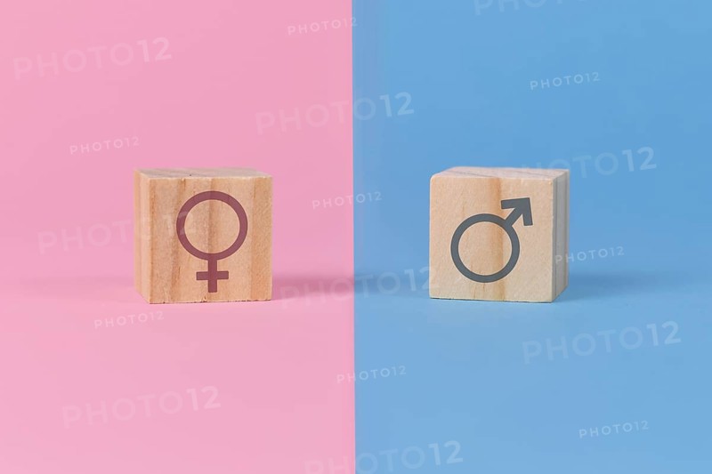 Gender stereotypes showing cubes with male and female signs on pink and blue background,