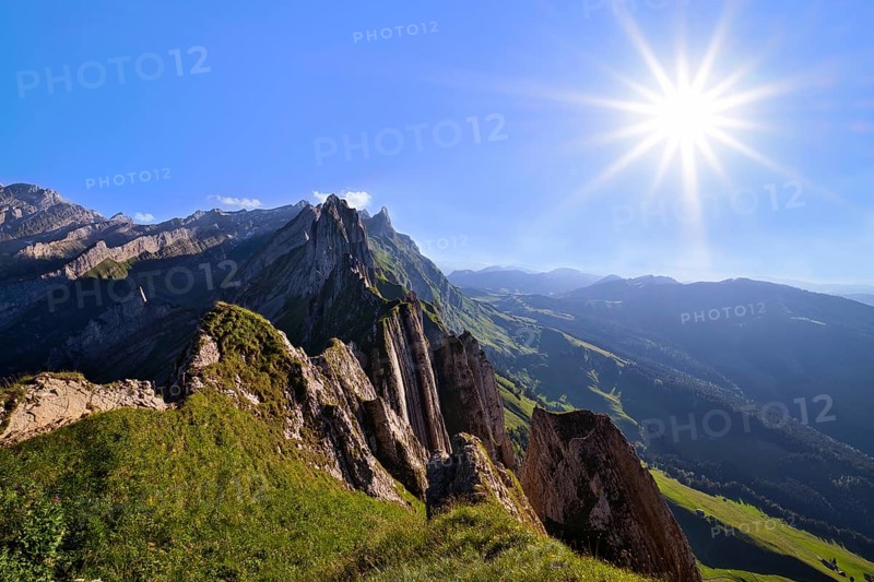 View of the Alpstein mountains in Appenzell, direct backlight with sun star in a cloudless sky