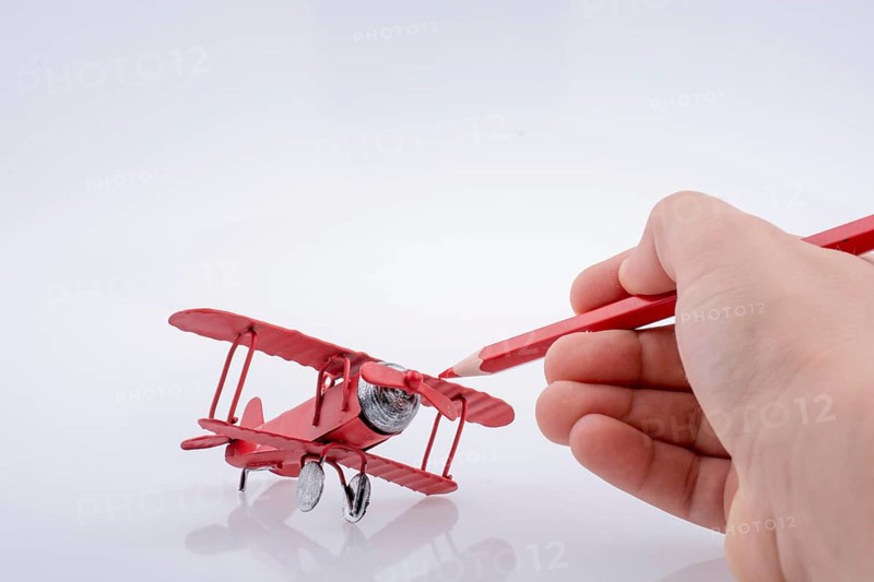 Red color pen in touch with little metal model airplane,