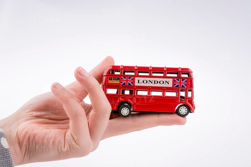 Hand holding a London double decker bus on a white background,