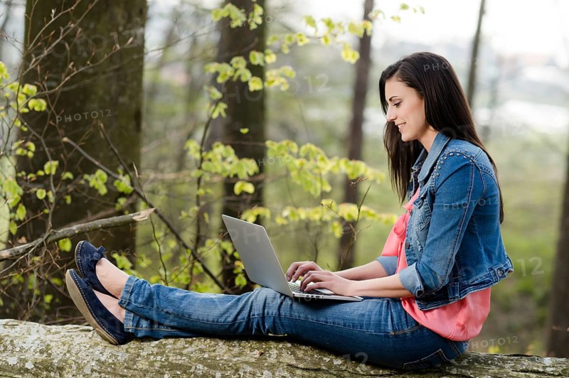 Young woman sitting in the forest with laptop,