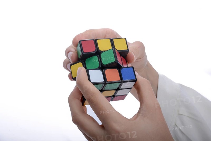 Child holding a Rubik's cube in hand on a white background,