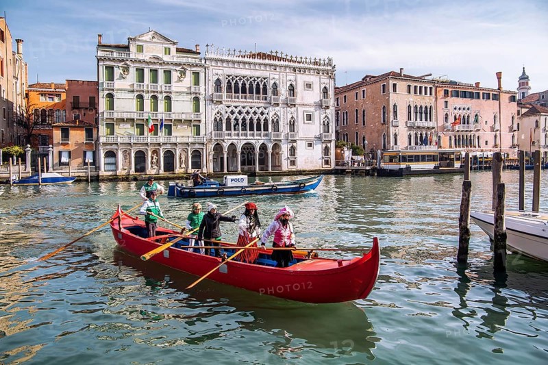 Rowing boat with carnival masks in front of Palazzo Ca dOro on the Grand Canal, Venice