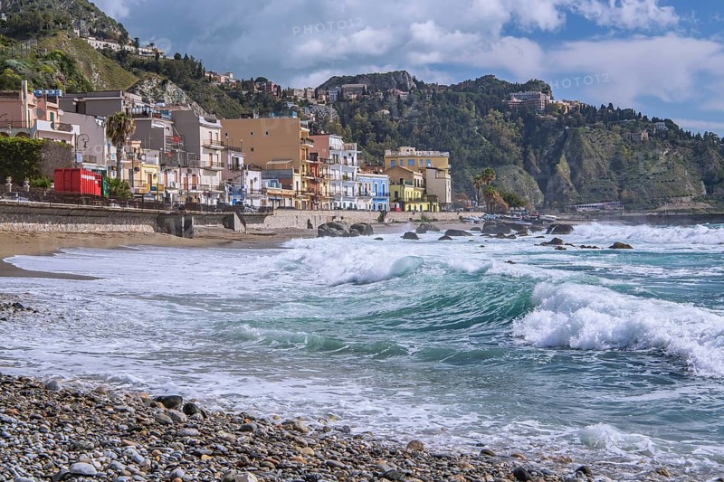 Sea surf in front of the promenade with Taormina on the hill, Giardini-Naxos