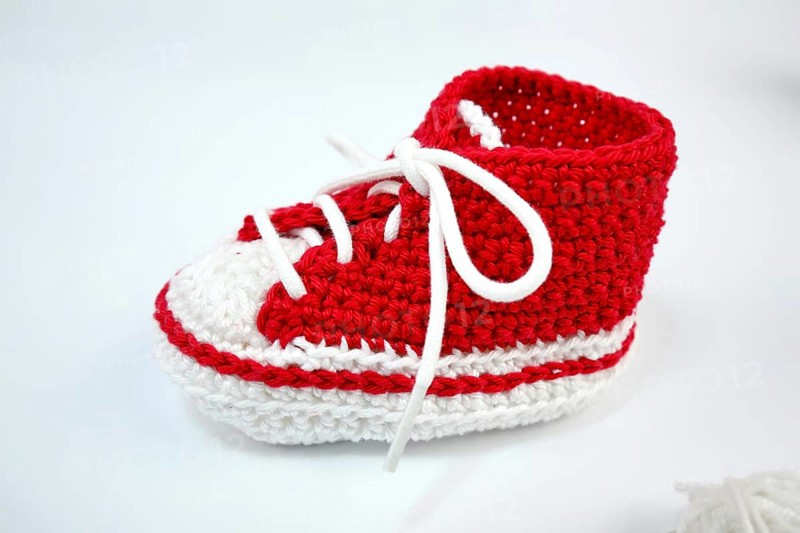 Baby shoes or crochet shoes in red and white isolated against a white background,