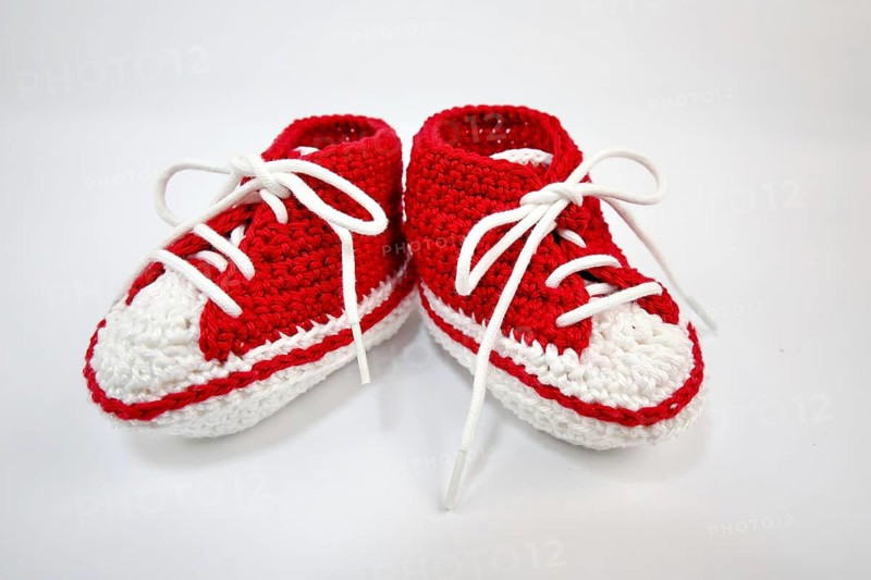 Baby shoes or crochet shoes in red and white isolated against a white background,