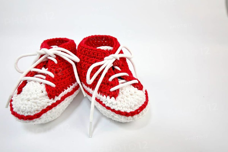 Baby shoes or crochet shoes in red and white isolated against a white background,
