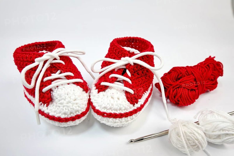 Baby shoes or crochet shoes in red and white isolated against a white background,