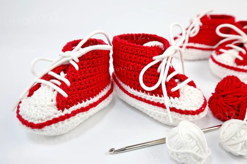 Baby shoes or crochet shoes in red and white isolated against a white background,