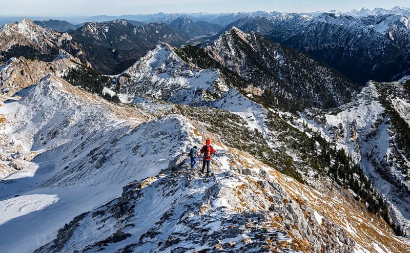 Two mountaineers on the narrow rocky snowy ridge of the Ammergauer Hochplatte, view towards Loesertaljoch