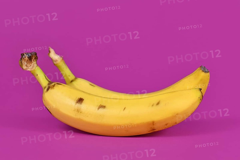 Ripe banana fruits with peel on purple background,