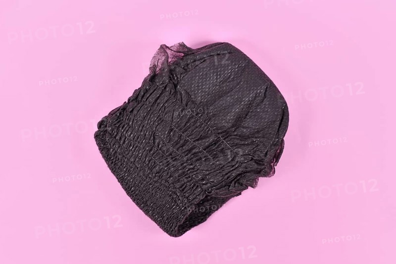 Black folded diaper for adult women on pink background,