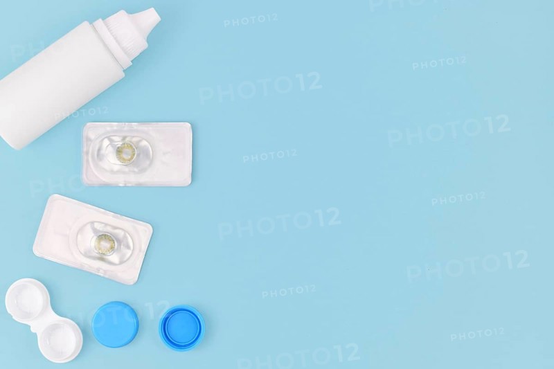 Packs with hazel green colored circle lenses, a type of contact lenses to enlarge eyes and change eye color with storage container and cleaning solution on side of blue background